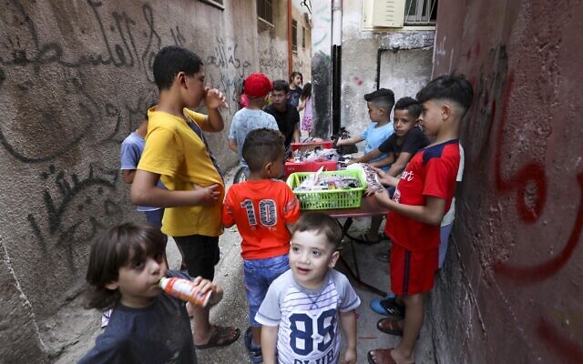Palestinian children gather around a street vendor in the Amari refugee camp near the West Bank city of Ramallah on July 29, 2020. (ABBAS MOMANI / AFP)