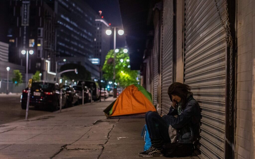 A homeless woman is seen sleeping on the street of Skid Row during the COVID-19, coronavirus pandemic in Los Angeles, California on May 16, 2020. (Apu Gomes/AFP via Getty Images)