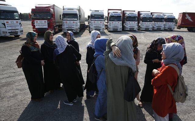 In this September 10, 2018 file photo, members of a Turkish pro-government aid group, wait for the departure of trucks carrying humanitarian aid destined for Idlib, Syria, in Istanbul. (AP Photo/Lefteris Pitarakis)