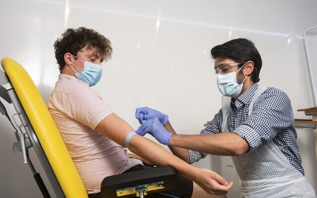 In this handout photo released by the University of Oxford, a doctor takes blood samples for use in a coronavirus vaccine trial in Oxford, England, on June 25, 2020. (John Cairns, University of Oxford via AP)
