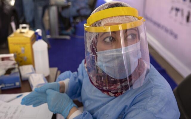 A health worker wearing protective gear prepares to take swab samples from people lining up in their cars to test for the coronavirus at a drive-through COVID-19 screening center at Ain Shams University in Cairo, Egypt on June 17, 2020. (AP Photo/Nariman El-Mofty)