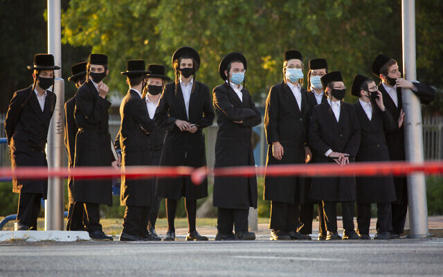 Ultra-Orthodox Jews wait to cross a closed road as they wear protective face masks to help curb the spread of the coronavirus in Ashdod, Israel, July 2, 2020 (AP Photo/Ariel Schalit)