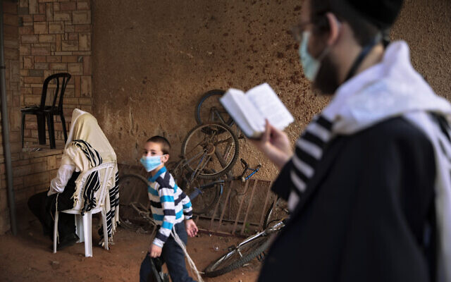 Jews pray next to their house as synagogues are limited to 20 people as per the government's measures to help stop the spread of the coronavirus in Bnei Brak, Israel, July 9, 2020. (Oded Balilty/AP)
