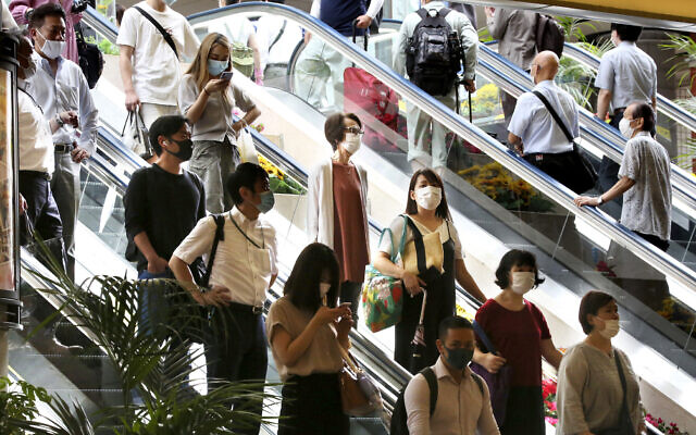 People wearing face masks to protect against the spread of the new coronavirus take an escalator at Yokohama station near Tokyo, July 22, 2020. (AP Photo/Koji Sasahara)