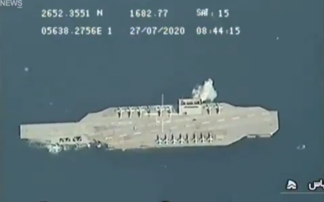 In video released on July 28, 2020, an explosion is seen next to a mock US aircraft carrier in the Strait of Hormuz during military exercises held by Iran's Islamic Revolutionary Guard Corps. (Screen capture/Twitter)