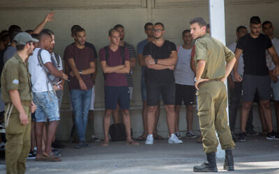 Young Israeli men line up as they arrive at the IDF recruitment center at Tel Hashomer on July 26, 2018. (Miriam Alster/Flash90)