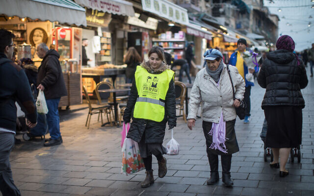 A young woman helps an elderly lady with her grocery bags at the Mahane Yehuda Market in Jerusalem, February 14, 2019. (Hadas Parush/Flash90)