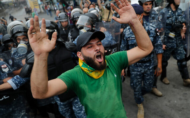 A Hezbollah supporter shouts slogans in front of riot police during a protest against the US near its embassy in Aukar, northeast of Beirut, Lebanon, July 10, 2020. (AP Photo/Hussein Malla)