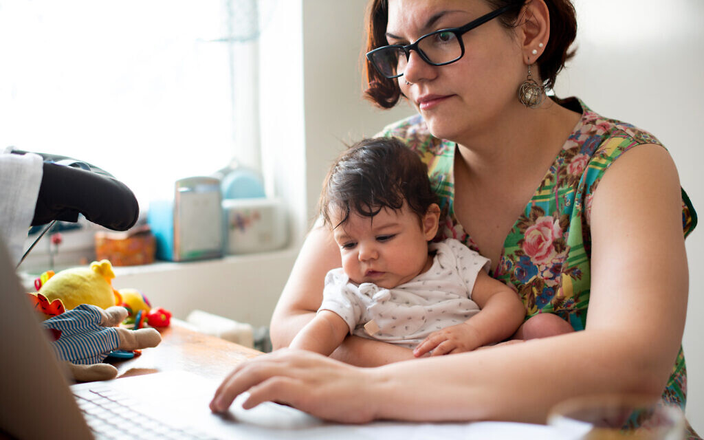 Working mom with baby in a lap (StockRocket; iStock by Getty Images)