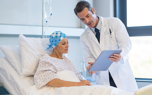 A doctor shows medical records to cancer patient in hospital ward (iStock)