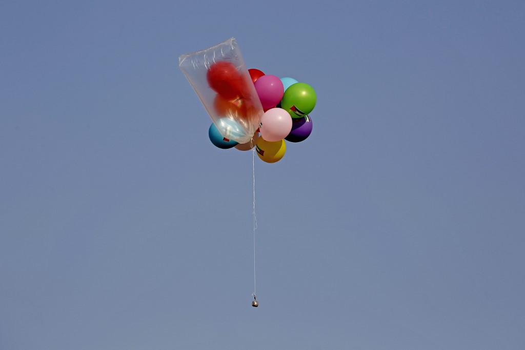 Balloons carrying an incendiary device float in the air upon release by Palestinians near Gaza’s Bureij refugee camp, by the Israel-Gaza border fence, on August 12, 2020. (Mohammed Abed/AFP)