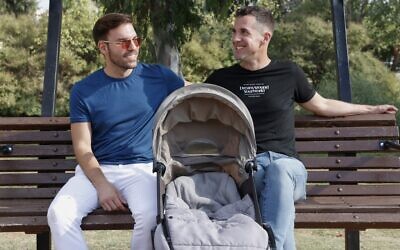 Harel Barak (R) and his husband Yakir Kanneli (L) pose for a picture with an empty stroller at a park in Tel Aviv, on August 14, 2020. (Photo by JACK GUEZ / AFP)