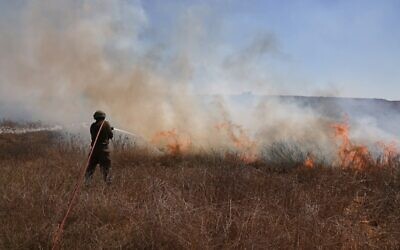 An Israeli soldier extinguishes a fire in a field close to the southern kibbutz of Nir Am, near the border with the Gaza Strip on August 25, 2020, after it was set off by incendiary balloons launched from the Palestinian enclave. (Menahem KAHANA / AFP)