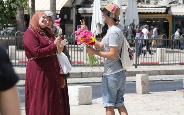 Illustrative: An activist with Tag Meir, an Israeli group funded by the New Israel Fund, hands out flowers on a day to counter racism in Jerusalem on June 1, 2019. (NIF/Yossi Zamir via JTA)