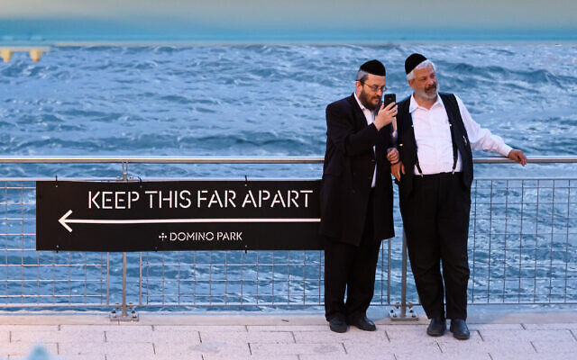 Orthodox men stand next to a social distancing sign in Williamsburg, Brooklyn, July 16, 2020. (Noam Galai/Getty Images/via JTA)