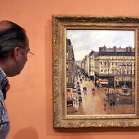 This May 12, 2005 file photo shows a visitor viewing the Impressionist painting called "Rue St.-Honore, Apres-Midi, Effet de Pluie" painted in 1897 by Camille Pissarro, on display in the Thyssen-Bornemisza Museum in Madrid. (AP Photo/Mariana Eliano, File)
