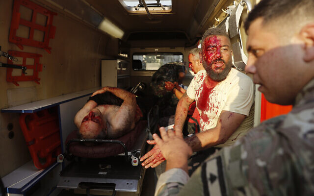 A Lebanese soldier, right, checks injured men who sit inside an ambulance at the explosion scene that hit the seaport of Beirut, Lebanon, Tuesday, Aug. 4, 2020. (AP Photo/Hussein Malla)