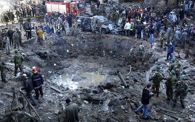 Rescue workers and soldiers stand around a massive crater after a bomb attack that tore through the motorcade of former prime minister Rafik Hariri, in Beirut, Lebanon, February 14, 2005. (AP Photo)