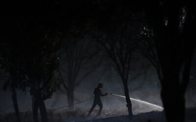 A volunteer attempts to extinguish a fire started by an incendiary device launched from the Gaza Strip, on the Israeli side of the border between Israel and Gaza, Monday, Aug. 24, 2020.  (AP Photo/Ariel Schalit)