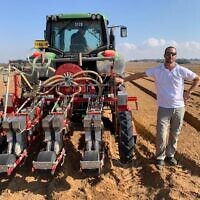 Dotan Borenstein, CEO of SaliCrop, stands next to a tractor distributing carrot seeds for a field trial near the Gaza border, August 23, 2020. (Courtesy)