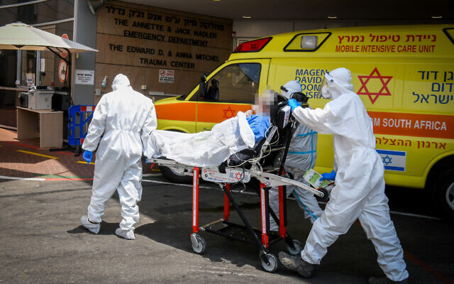 Illustrative: Magen David Adom workers wearing protective clothing move a patient outside the coronavirus unit at the Sheba Medical Center in Ramat Gan on July 27, 2020. (Yossi Zeliger/Flash90)