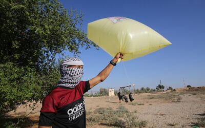 Palestinian men prepare to release balloon-borne explosive and incendiary devices toward Israel near Rafah, along the Israel-Gaza border, on August 21, 2020 (Fadi Fahd/Flash90)
