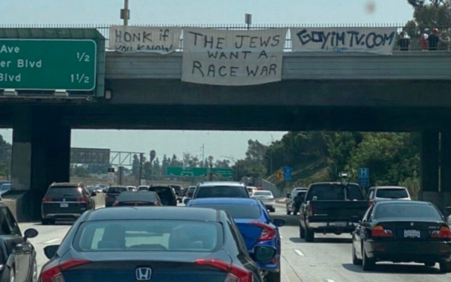 Illustrative: A sign bearing the slogan, 'Honk if you know the Jews want a race war' placed on an overpass on route I-405 in Los Angeles by Jon Minadeo Jr. of the Goyim Defense League. (Siamak Kordestani/Twitter via JTA)