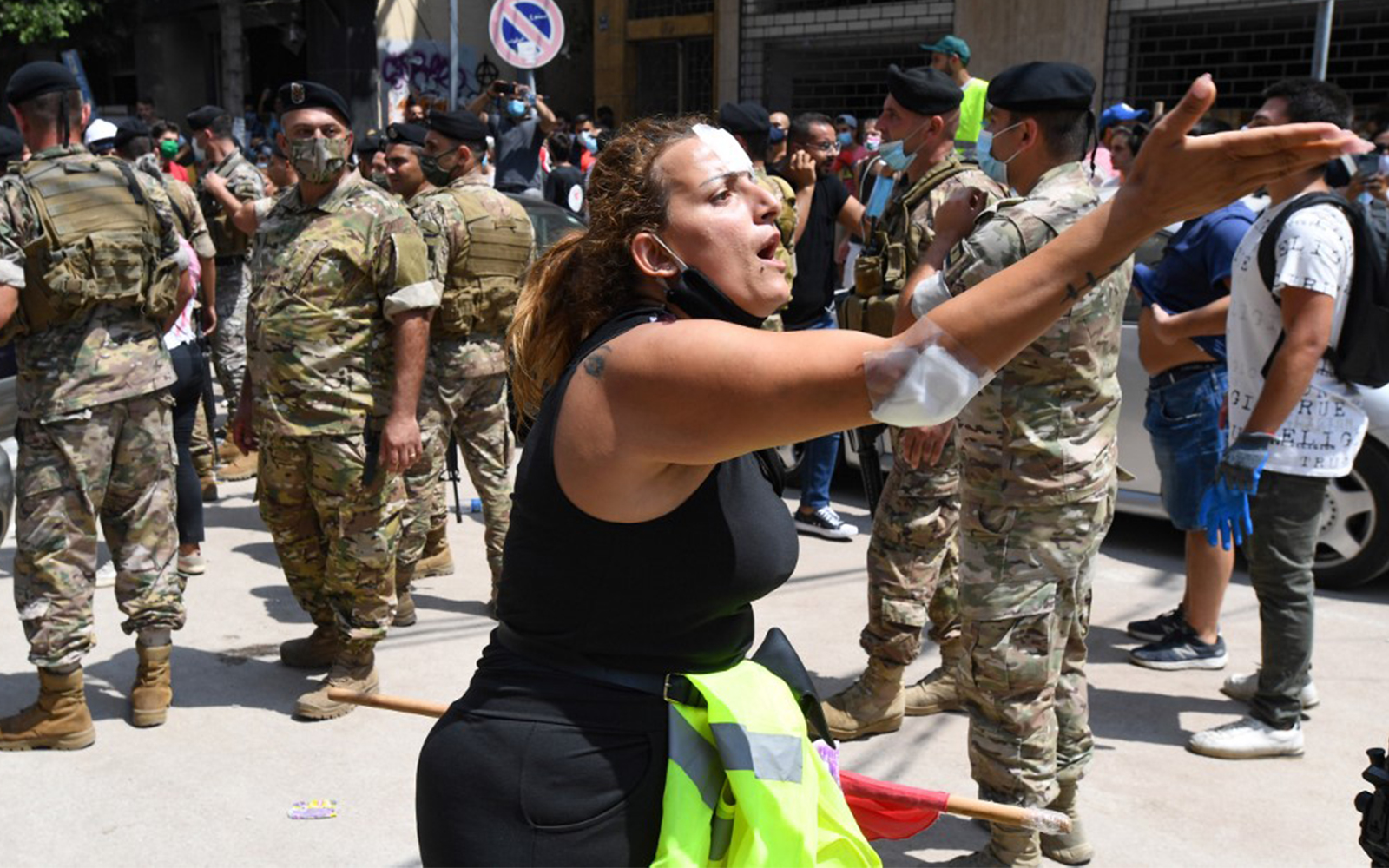 An injured Lebanese anti-government protester reacts as members of Lebanon’s security forces stand guard in the during a visit by French President Emmanuel Macron, August 6, 2020. (AFP)