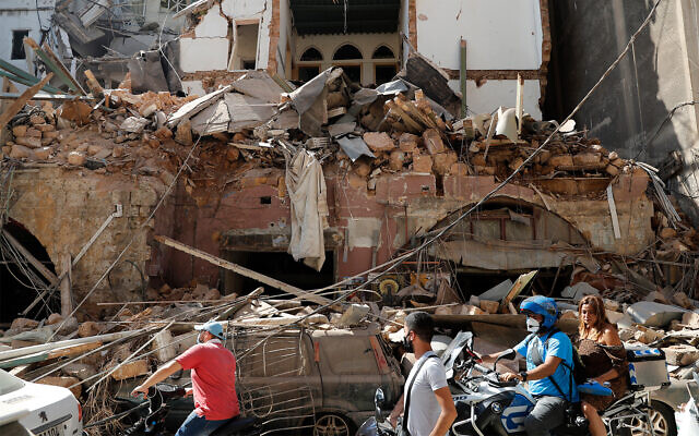 Citizens ride their scooters and motorcycles in front of a house that was destroyed in a massive explosion in the seaport of Beirut, Lebanon, August 5, 2020. (AP Photo/Hussein Malla)