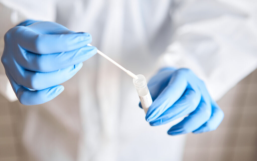 Illustrative: A doctor holds a swab and a test tube (Malkovstock; iStock by Getty Images)