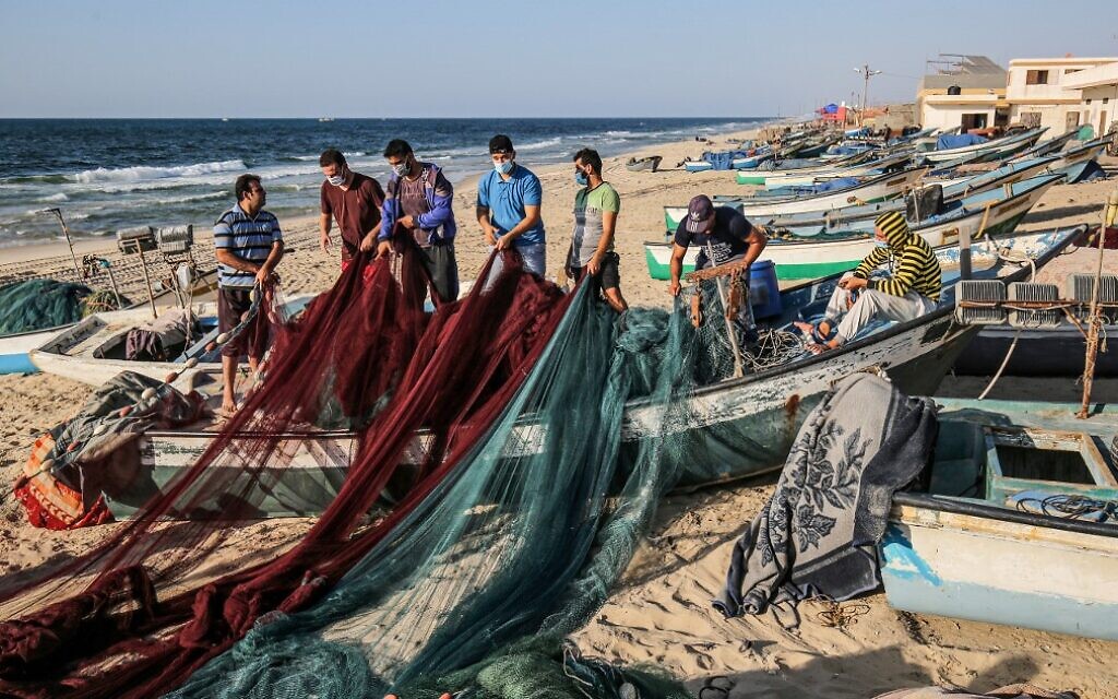 Palestinian fishermen, mask-clad due to the COVID-19 coronavirus pandemic, prepare their fishnets along a beach off the Mediterranean Sea in Rafah in the southern Gaza Strip on September 2, 2020. (SAID KHATIB / AFP)