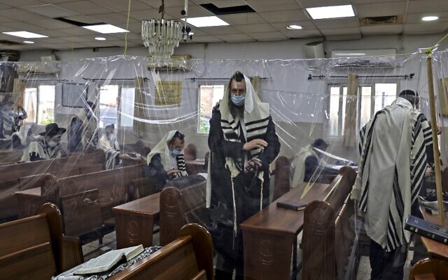 Ultra-Orthodox Jews praying in a synagogue divided with plastic sheets in Bnei Brak, near Tel Aviv, amid measures put in place to stem the spread of COVID-19, on September 7, 2020. (Menahem Kahana/AFP)