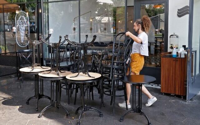An employee puts away the furniture of a restaurant in the coastal city of Tel Aviv on September 18, 2020, ahead of a nationwide lockdown to tackle a spike in coronavirus cases. (JACK GUEZ/AFP)