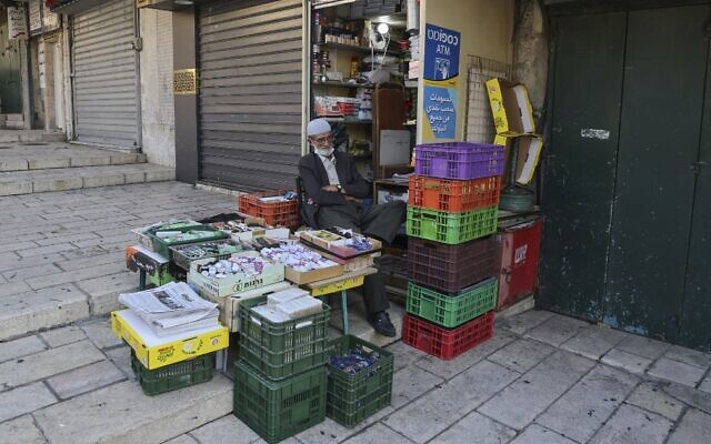 A Palestinian shop owner sits next to his merchandise on an otherwise empty street in Jerusalem's Old City, on September 19, 2020, amid a nationwide lockdown due to a spike in coronavirus infections. (Menahem Kahana/AFP)