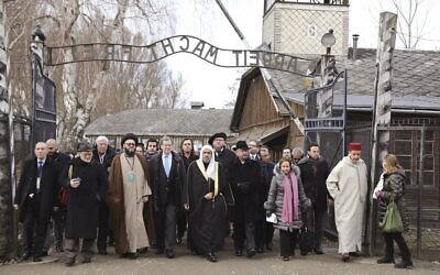 In this January 23, 2020, file photo, a delegation of Muslim religious leaders gather at the gate leading to the former Nazi death camp of Auschwitz, together with a Jewish group in what organizers called 'the most senior Islamic leadership delegation' to visit the former death camp in Oswiecim, Poland. (American Jewish Committee via AP, File)
