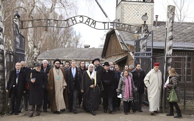 In this January 23, 2020, file photo, a delegation of Muslim religious leaders gather at the gate leading to the former Nazi death camp of Auschwitz, together with a Jewish group in what organizers called 'the most senior Islamic leadership delegation' to visit the former death camp in Oswiecim, Poland. (American Jewish Committee via AP, File)