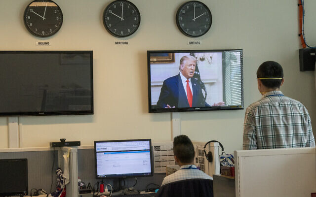 Reporters with the Xinhua Press Agency watch as US President Donald Trump is seen on a video screen remotely addressing the 75th session of the United Nations General Assembly on September 22, 2020, at UN headquarters. (AP/Mary Altaffer)