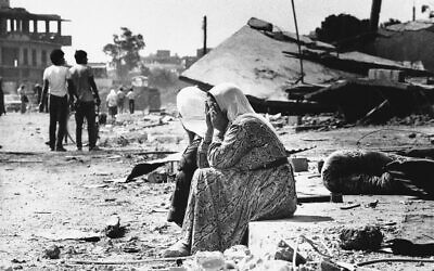 Two Palestinian women weep as they sit on the curb in the Sabra Palestinian refugee camp in West Beirut, Lebanon, September 19, 1982, after they found bodies of relatives. (AP Photo/Bill Foley)