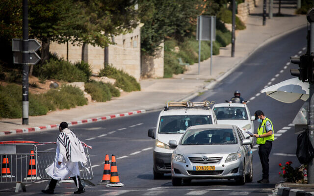A Jewish man walks with a prayer shawl near a temporary checkpoint outside the East Jerusalem neighborhood of Sheikh Jarrah, on September 19, 2020, during a nationwide lockdown (Yonatan Sindel/Flash90)