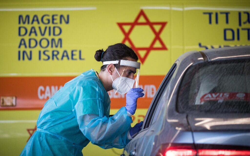 A medical team member wearing protective gear takes a swab from a woman to test for COVID-19, outside the coronavirus unit at Shaare Zedek hospital in Jerusalem on September 24, 2020. (Yonatan Sindel/Flash90)