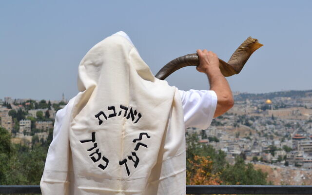 A man blows the shofar, or ram's horn, traditionally sounded on the Jewish new year of Rosh Hashanah, while wearing a prayer shawl emblazoned with the Hebrew phrase meaning, 'Love thy neighbor as thyself.' (Courtesy Moshe Silver)