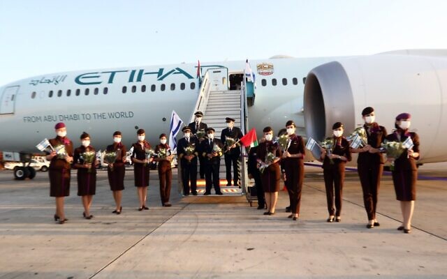 The crew of an Etihad Airlines flight wave Israeli flags after landing at Ben Gurion Airport, October 19, 2020 (Sivan Farag)