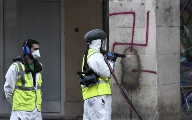 A municipal worker cleans swastikas spray painted on columns of the Rivoli Street in central Paris, on October 11, 2020. (Stephane De Sakutin/AFP)