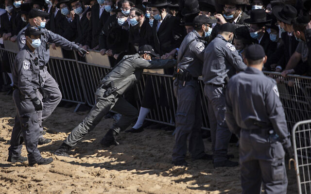 Israeli police try to control a crowd of mourners during the funeral of Rabbi Mordechai Leifer, the latest in a string of clashes between security forces and ultra-Orthodox Jews violating a national coronavirus lockdown order, in the port city of Ashdod, Israel, Monday, Oct. 5, 2020. (AP Photo/Tsafrir Abayov)