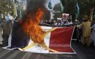 Supporters of religious groups burn a representation of a French flag during a rally against French President Emmanuel Macron and the republishing of caricatures of the Prophet Muhammad they deem blasphemous, in Lahore, Pakistan, Oct. 30, 2020. (AP Photo/K.M. Chaudary)