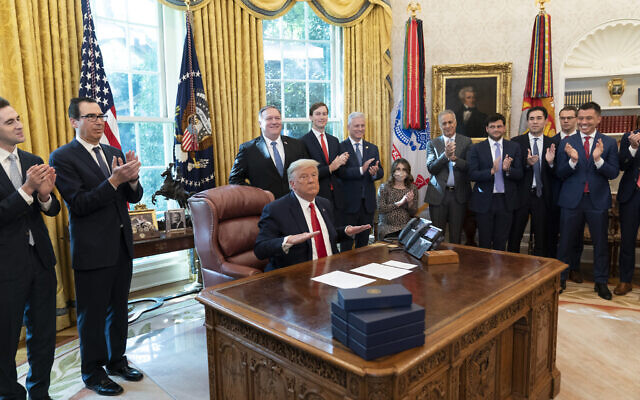 US President Donald Trump reacts after hanging up a phone call with the leaders of Sudan and Israel, as Treasury Secretary Steven Mnuchin, second from left, Secretary of State Mike Pompeo, White House senior adviser Jared Kushner, National Security Adviser Robert O'Brien, and others applaud in the Oval Office of the White House, Oct. 23, 2020, in Washington. (AP Photo/Alex Brandon)