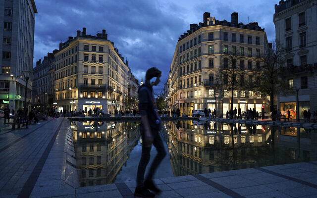 A man wearing a mask walks in the street in the center of Lyon, central France, Wednesday, Oct. 28, 2020. France is bracing for a potential new lockdown as the president prepares a televised address Wednesday aimed at stopping a fast-rising tide of virus patients filling French hospitals and a growing daily death toll.  (AP Photo/Laurent Cipriani)