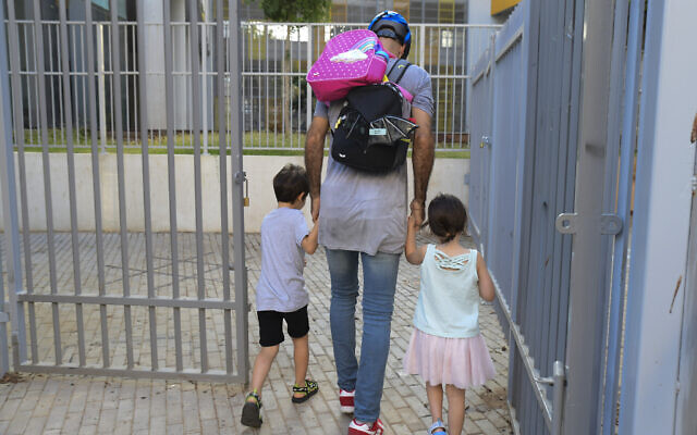 Parents accompany their children to the kindergarten in Tel Aviv as they return to kindergarten on October18, 2020, after being shut down during a national lockdown to prevent the spread of the Coronavirus. (Avshalom Sassoni/Flash90)