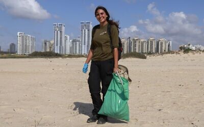 Israeli Lotem Benbenishti, 28, poses as she works on her new job collecting trash on the beach at the Peleg Nature reserve in the Mediterranean coastal city of Netanya on October 21, 2020. (Photo by MENAHEM KAHANA / AFP)