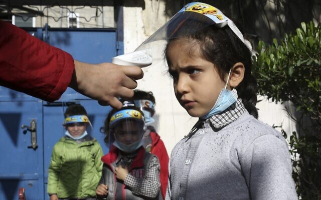 Palestinian children have their temperature checked as they arrive at a kindergarten in Gaza city while wearing face shields due to the COVID-19 pandemic, on November 23, 2020. (MOHAMMED ABED / AFP)